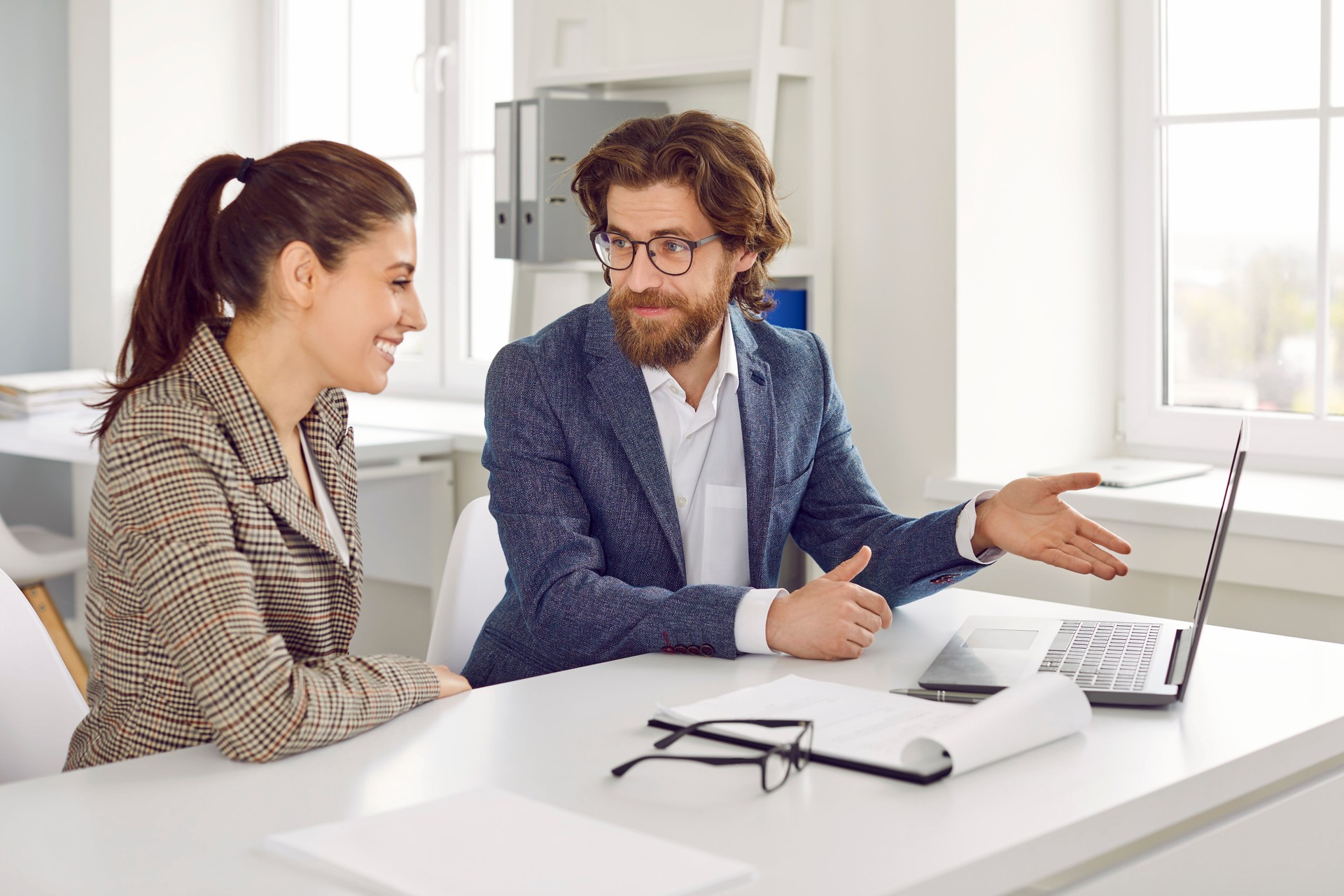 Real estate agent meeting with happy young woman and showing houses on laptop computer